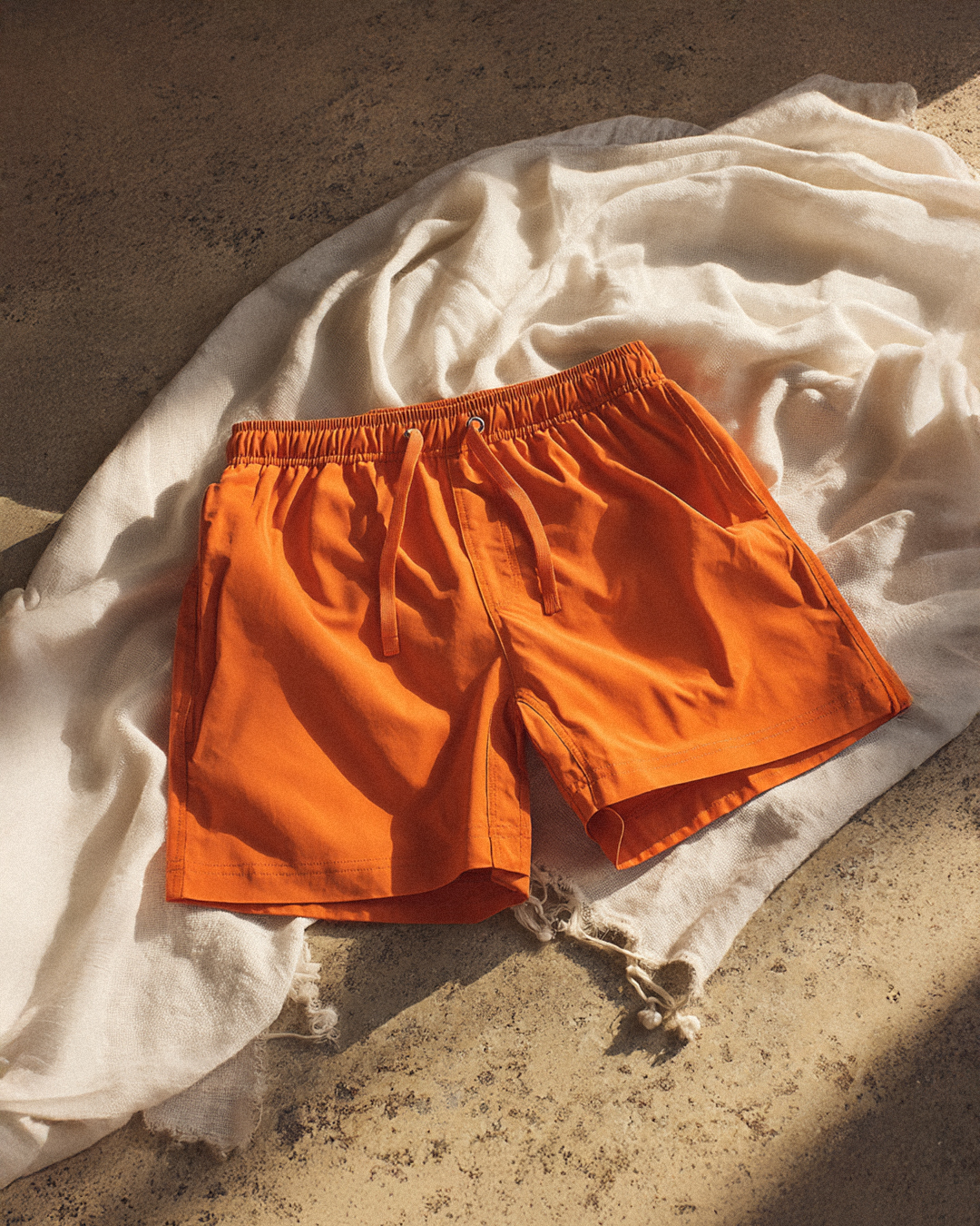 Orange shorts on a textured surface with a white cloth.