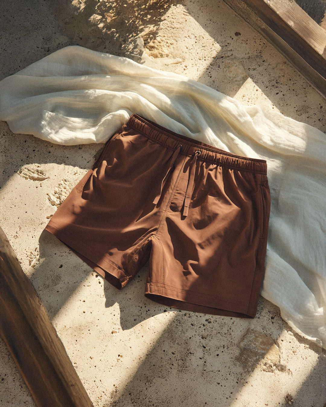 Brown shorts on a sandy surface with a white cloth.