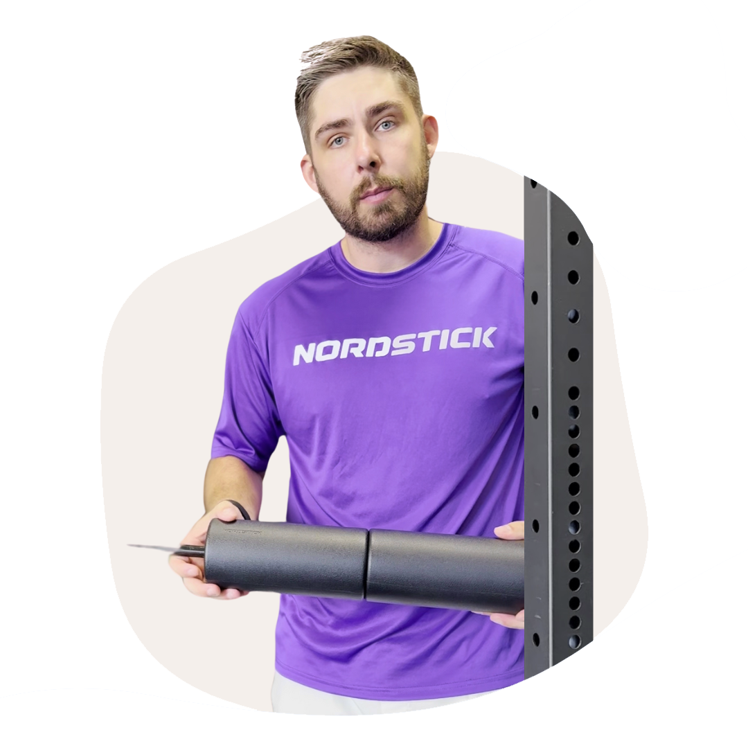 Person in purple shirt holding a black cylindrical object next to a metal frame.