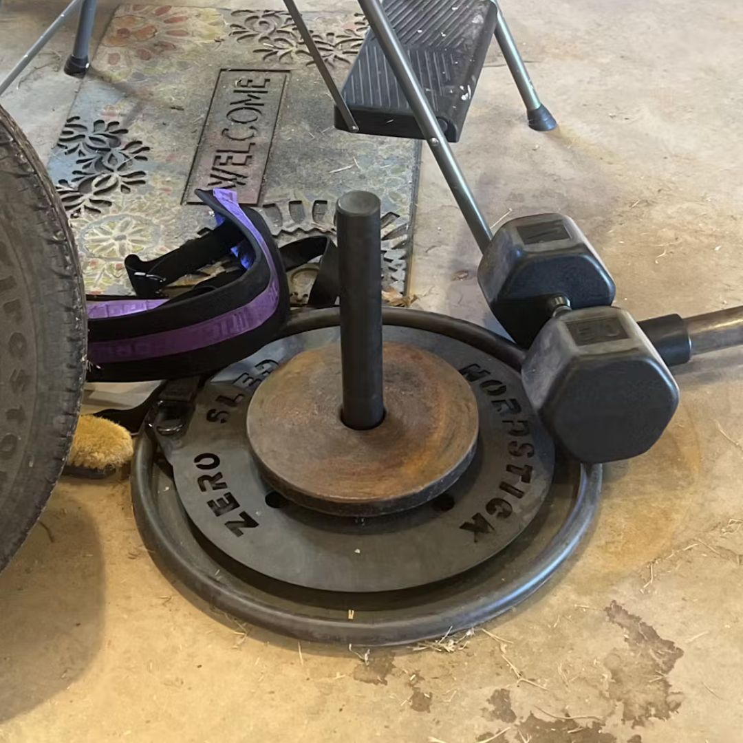 Garage gym setup with weights, a tire, and lifting accessories.