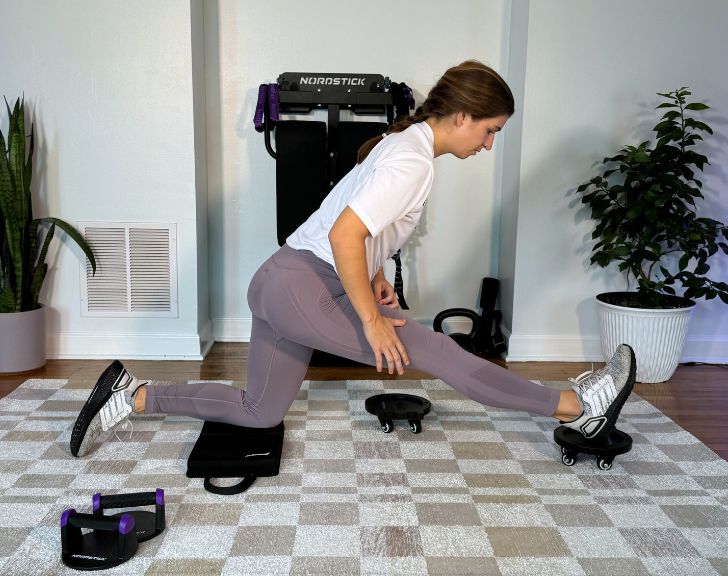 Woman stretching on exercise equipment in a home gym setting.