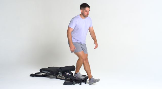 Man in casual workout attire using a gym machine.
