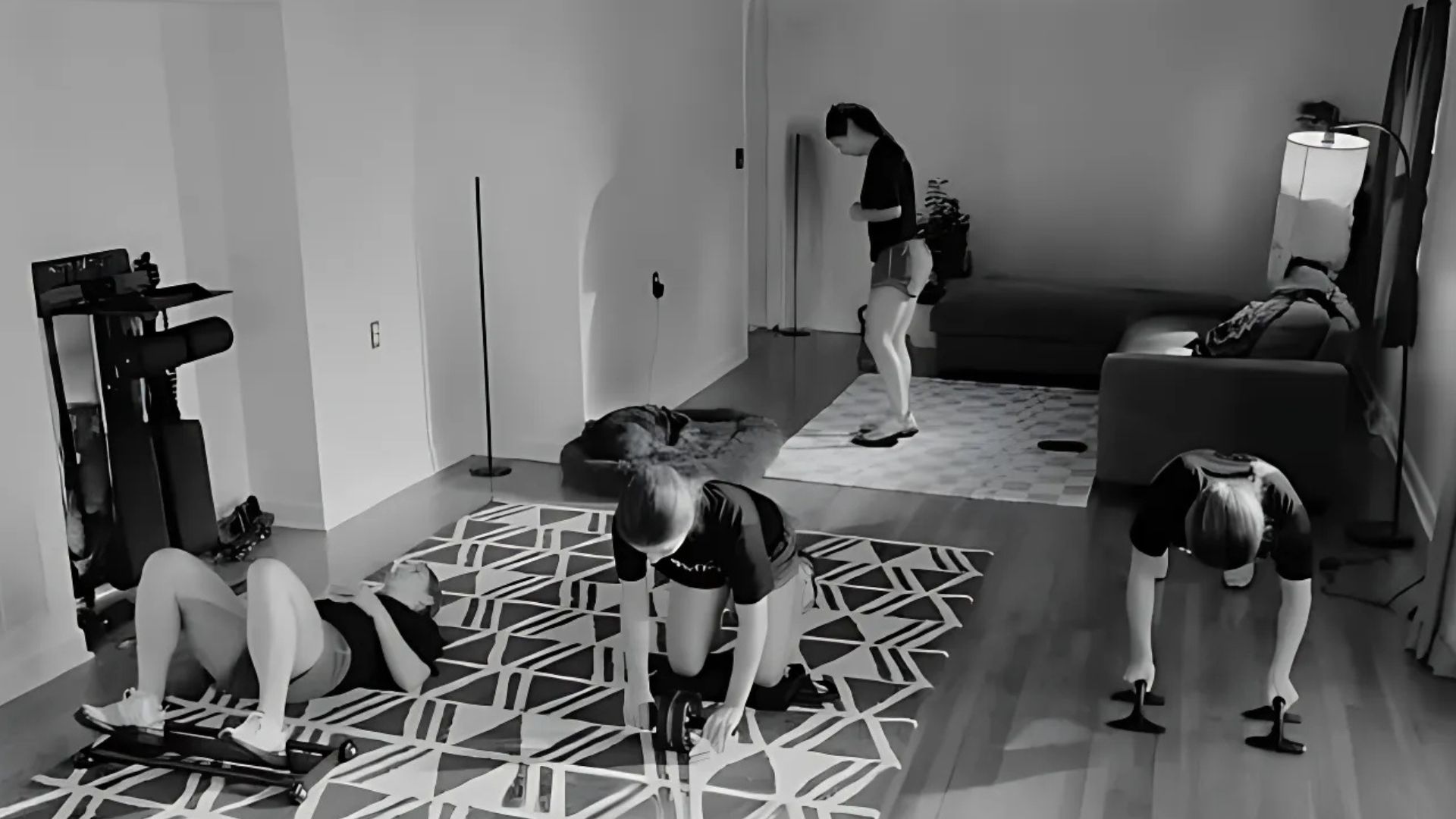 People exercising in a living room with various workout equipment.