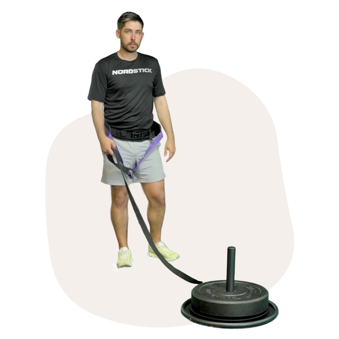 Man holding harness connected to a sled with weights.