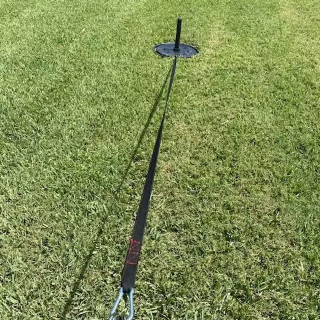 A resistance sled with a long strap on a grassy field.