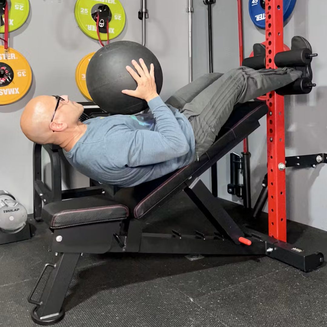 Person exercising on an incline bench with a medicine ball.
