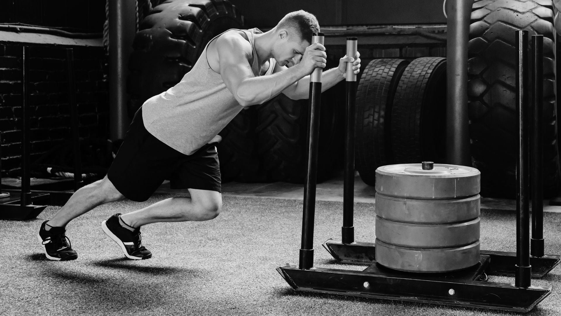 Man pushing a weighted sled in a gym.