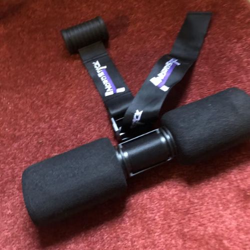 Black foam roller with straps on a red carpet.