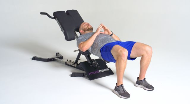 Man exercising on a NordicTrack bench, wearing a gray shirt and blue shorts.