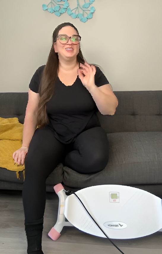 Person sitting on a sofa beside a balance board indoors.