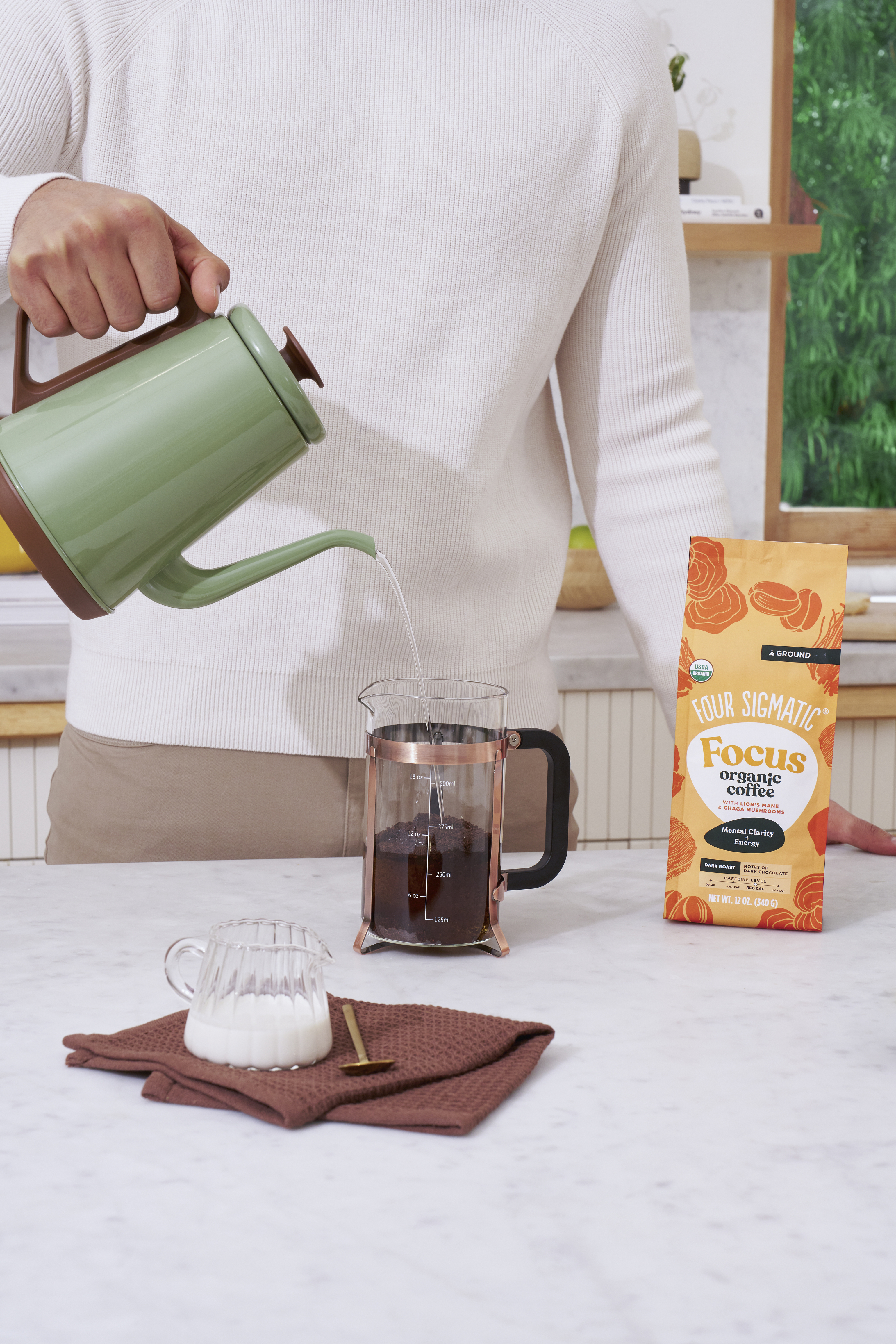 Person pouring water into a French press with coffee grounds.