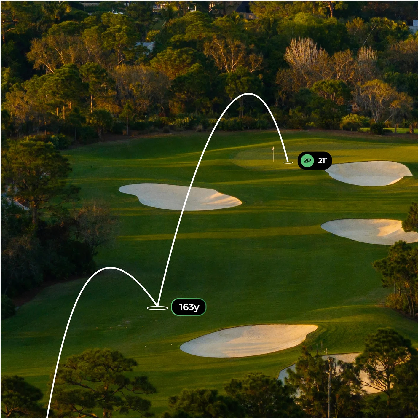 An aerial view of a golf course with a graphic overlay tracing a ball's trajectory to the hole.