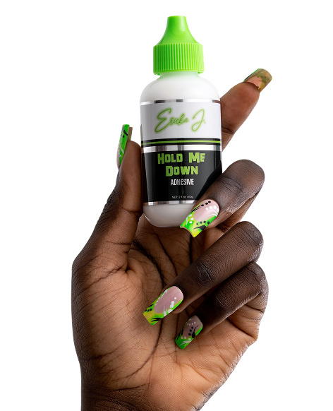 A hand with long, decorated green fingernails holds a bottle of Ericka J. Hold Me Down Adhesive.