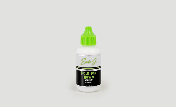 A white bottle of Ericka J. Hold Me Down Adhesive Sport with a bright green cap.