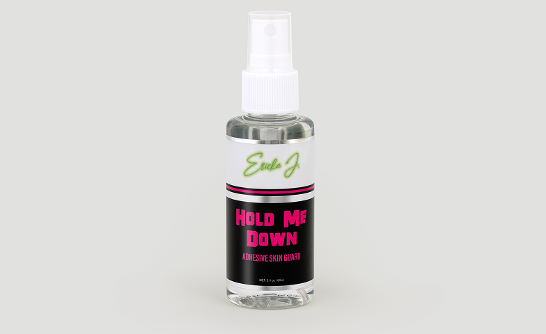 A clear spray bottle of Ericka J. Hold Me Down Adhesive Skin Guard against a plain background.
