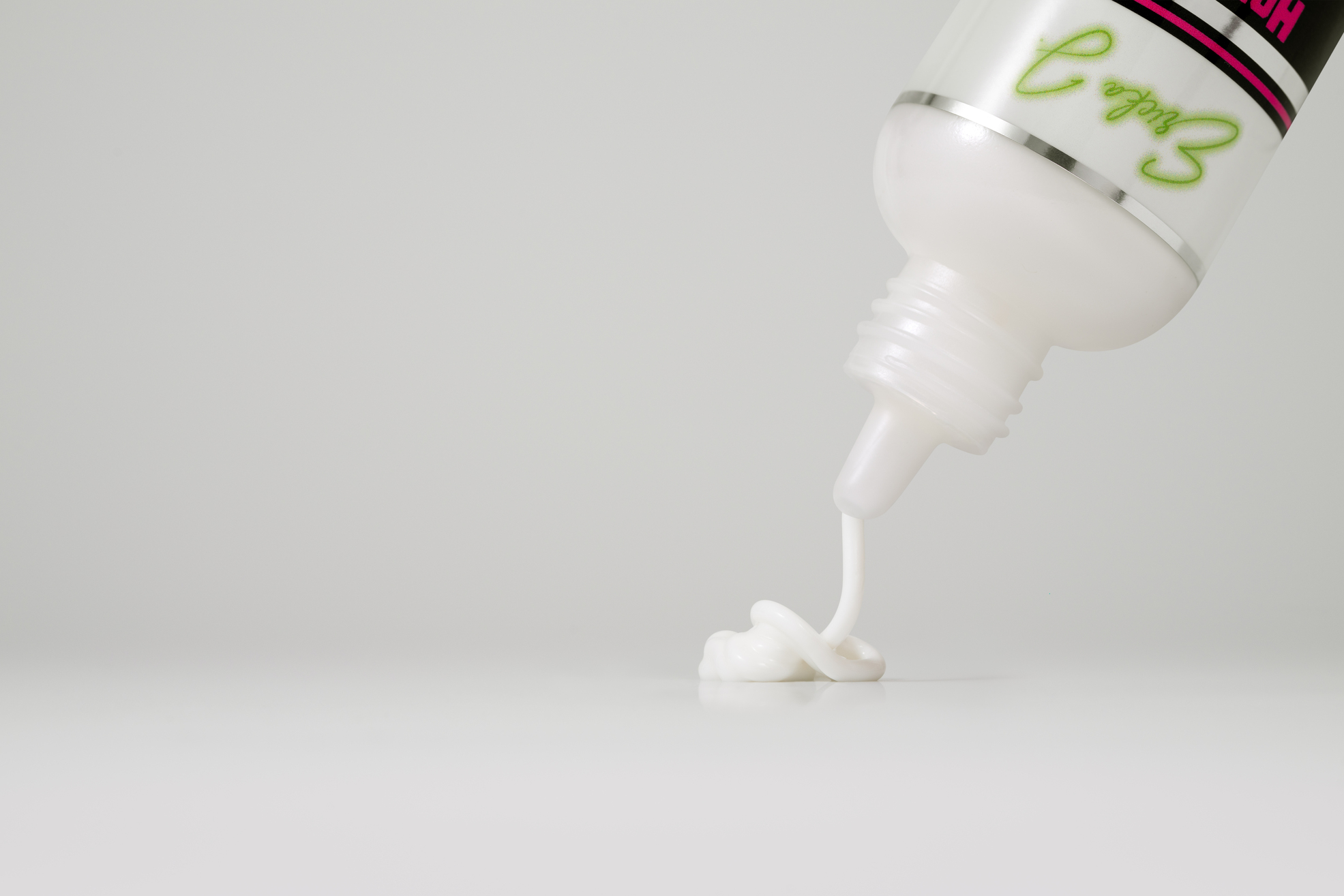 A close-up of a white lotion being dispensed from a bottle onto a white surface.