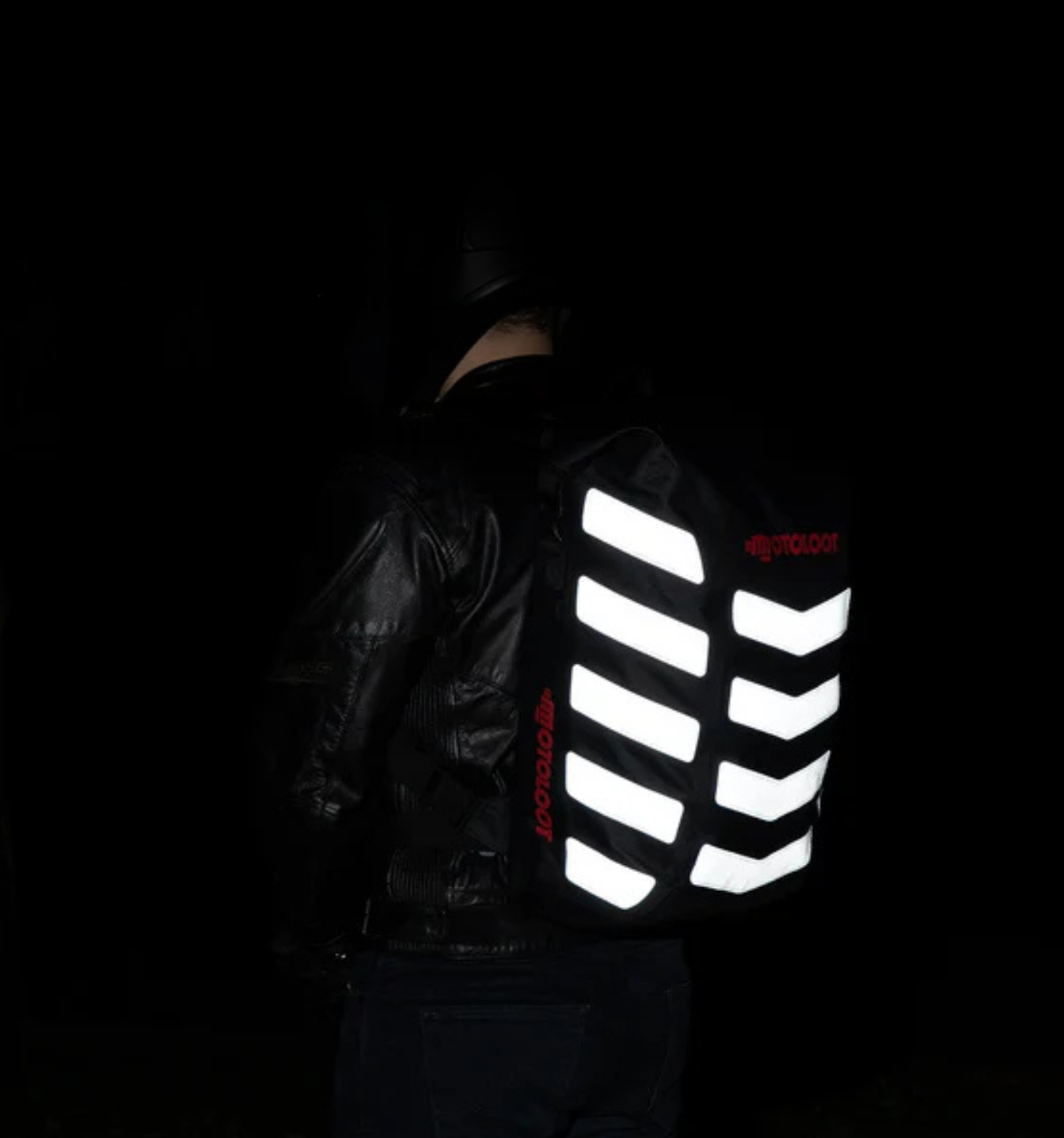 Person wearing a backpack with reflective stripes in a dark environment.