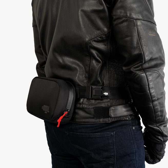Person wearing a black leather jacket with a small black waist bag.