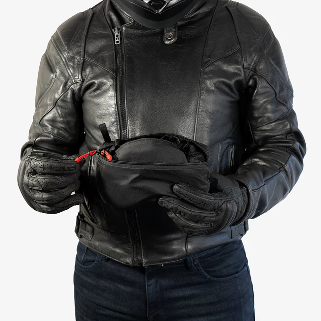 Person in black leather jacket holding a small black bag.