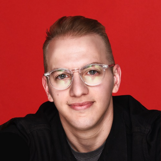 Person with glasses smiling against a red background.