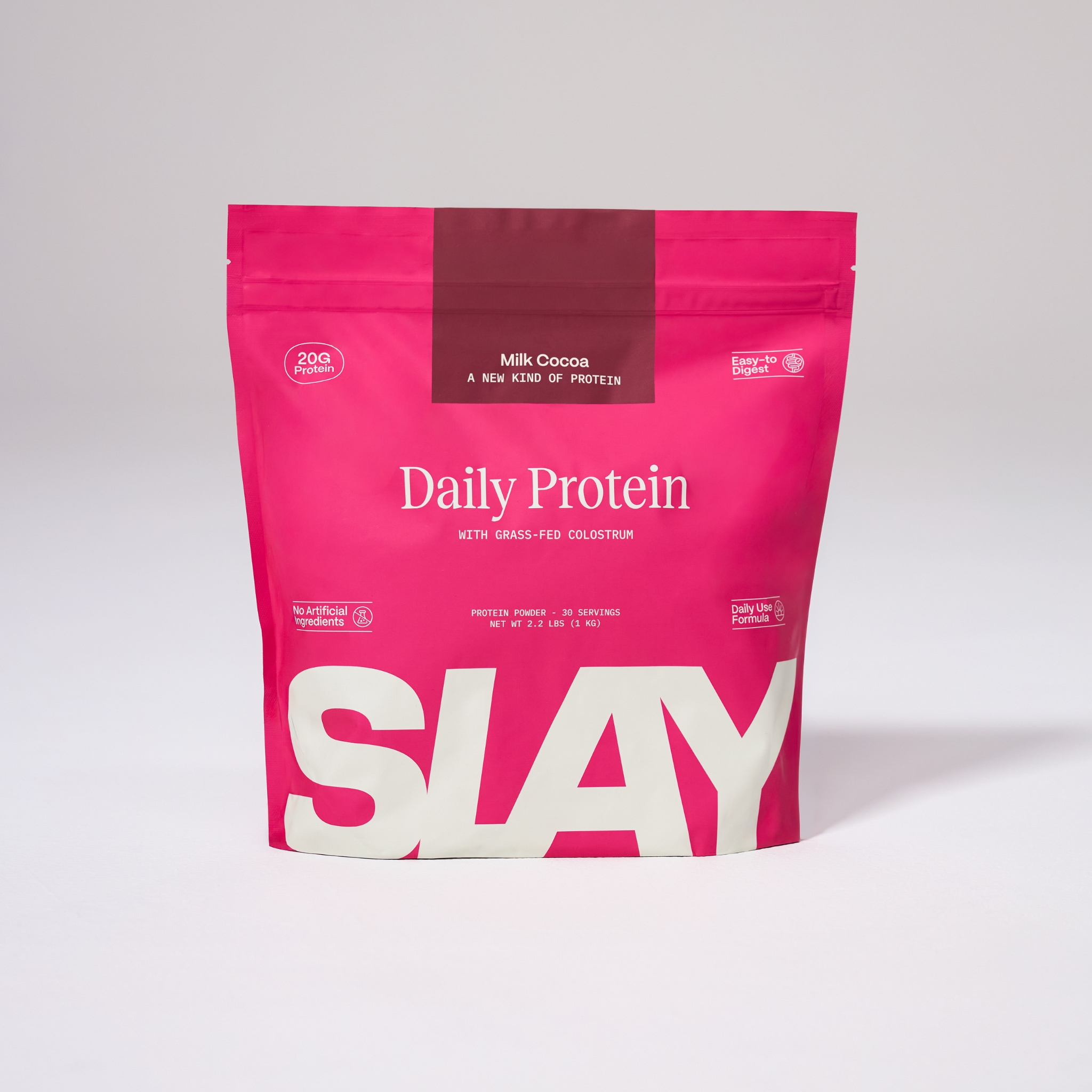A pink bag of Slay Daily Protein powder in Milk Cocoa flavor against a plain background.