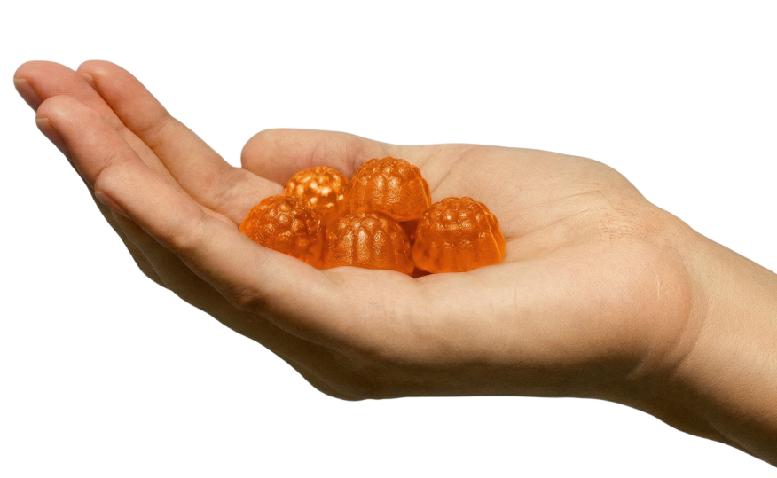 A close-up of a cupped hand holding several orange, dome-shaped gummy vitamins against a white background.