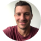 A slightly blurry, circular headshot of a smiling man in a maroon t-shirt.