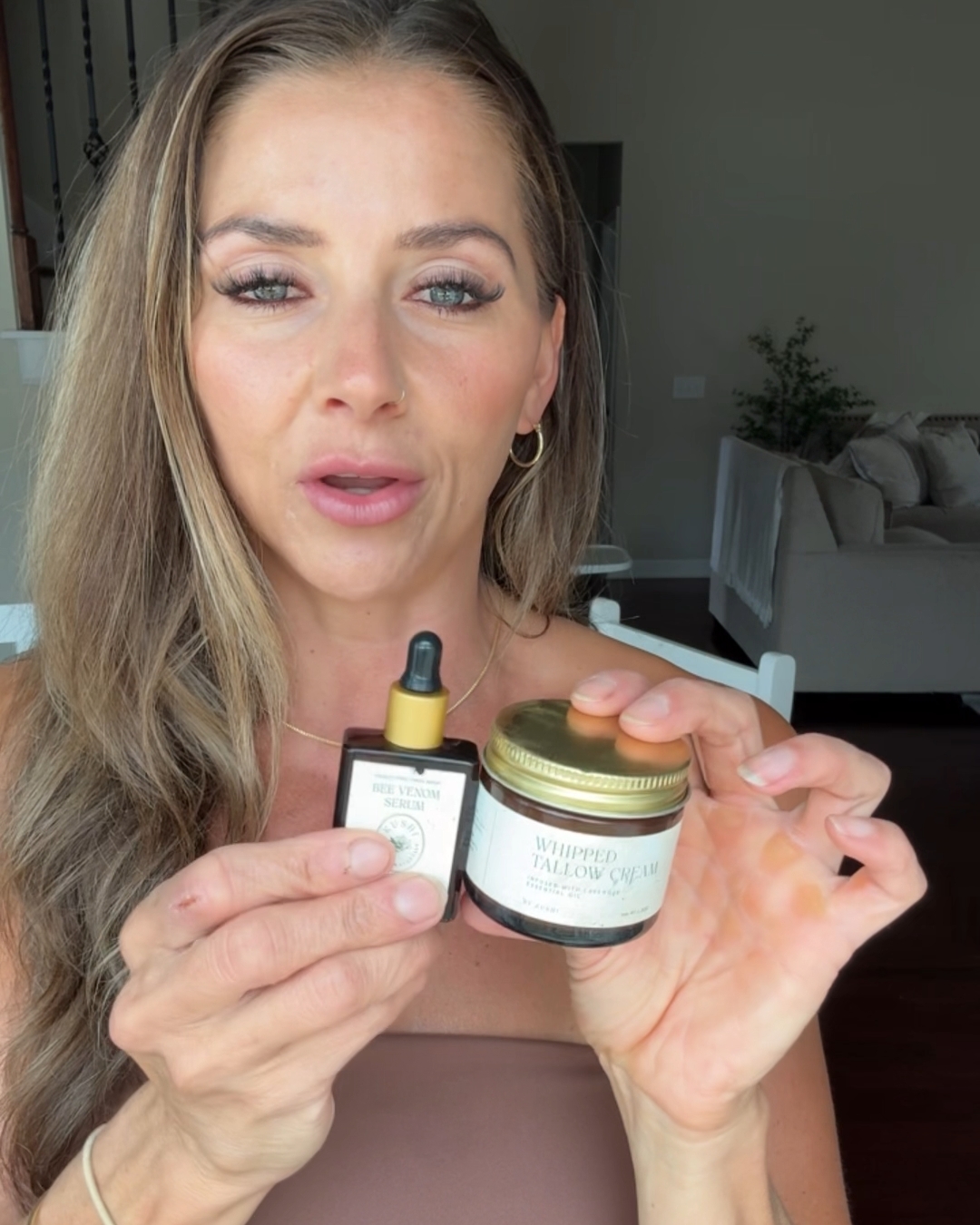 Person holding skincare product bottles indoors.