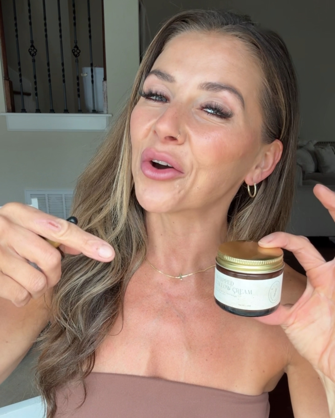 Person holding a jar labeled 'whipped tallow cream' and smiling.