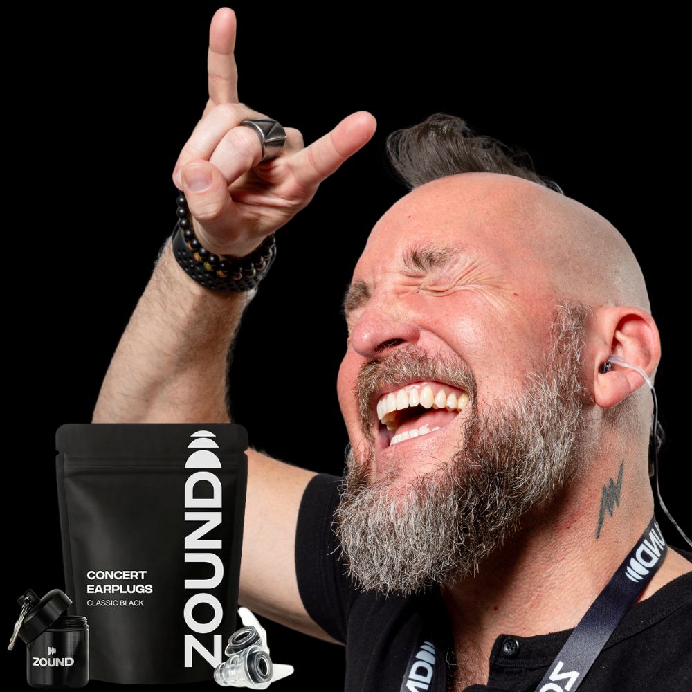 Man enjoying music with earplugs, hand raised in rock gesture.