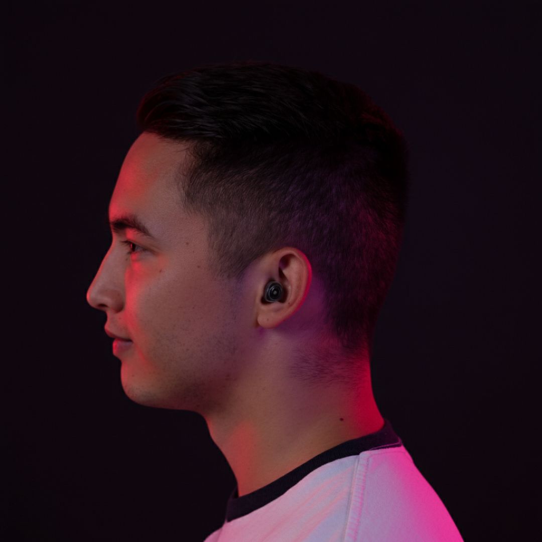 Person in profile with earbuds, lit by pink and purple light.