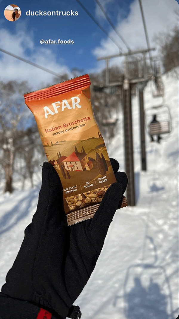 Afar savory protein bar in hand while skiing