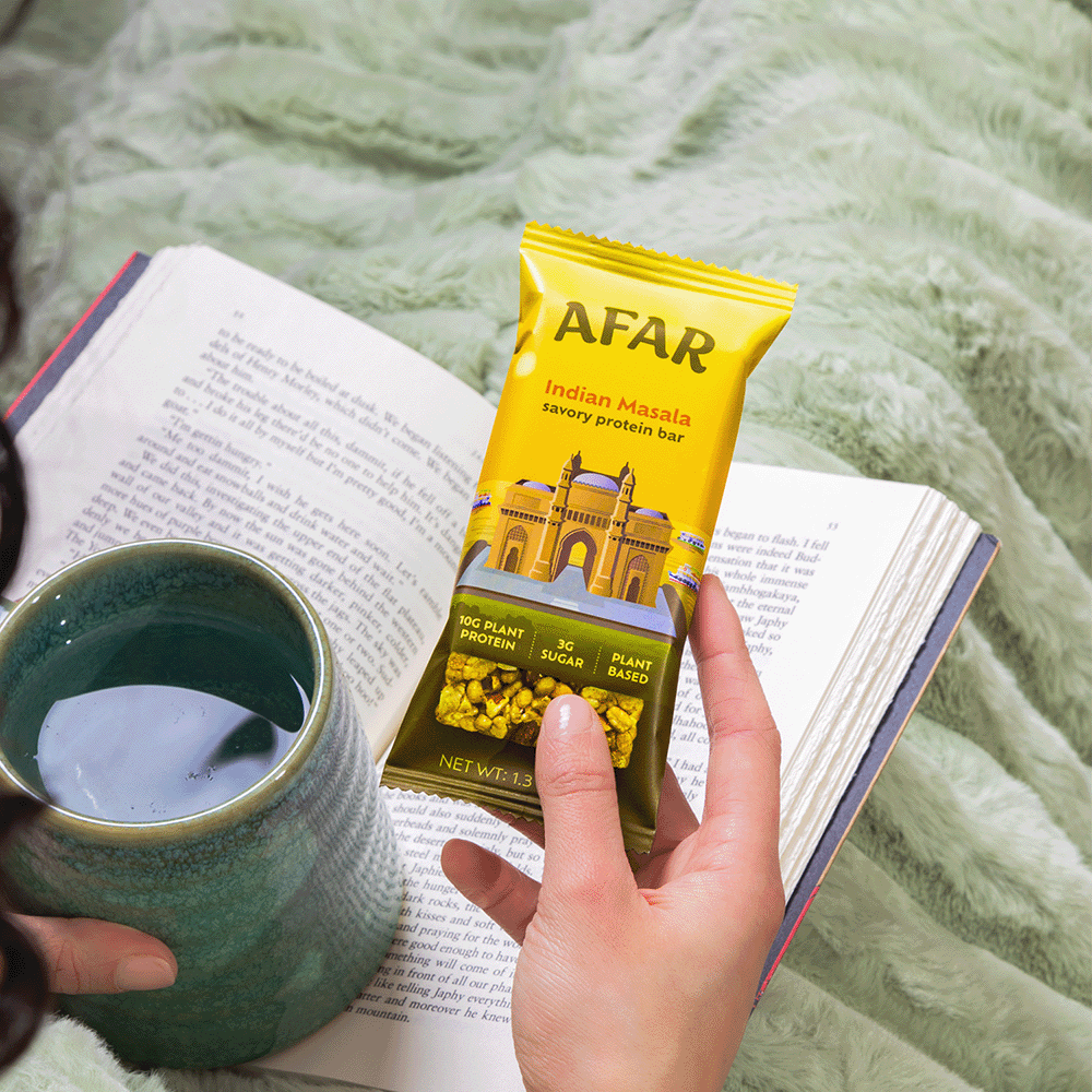 Woman holding Afar savory protein bar while reading