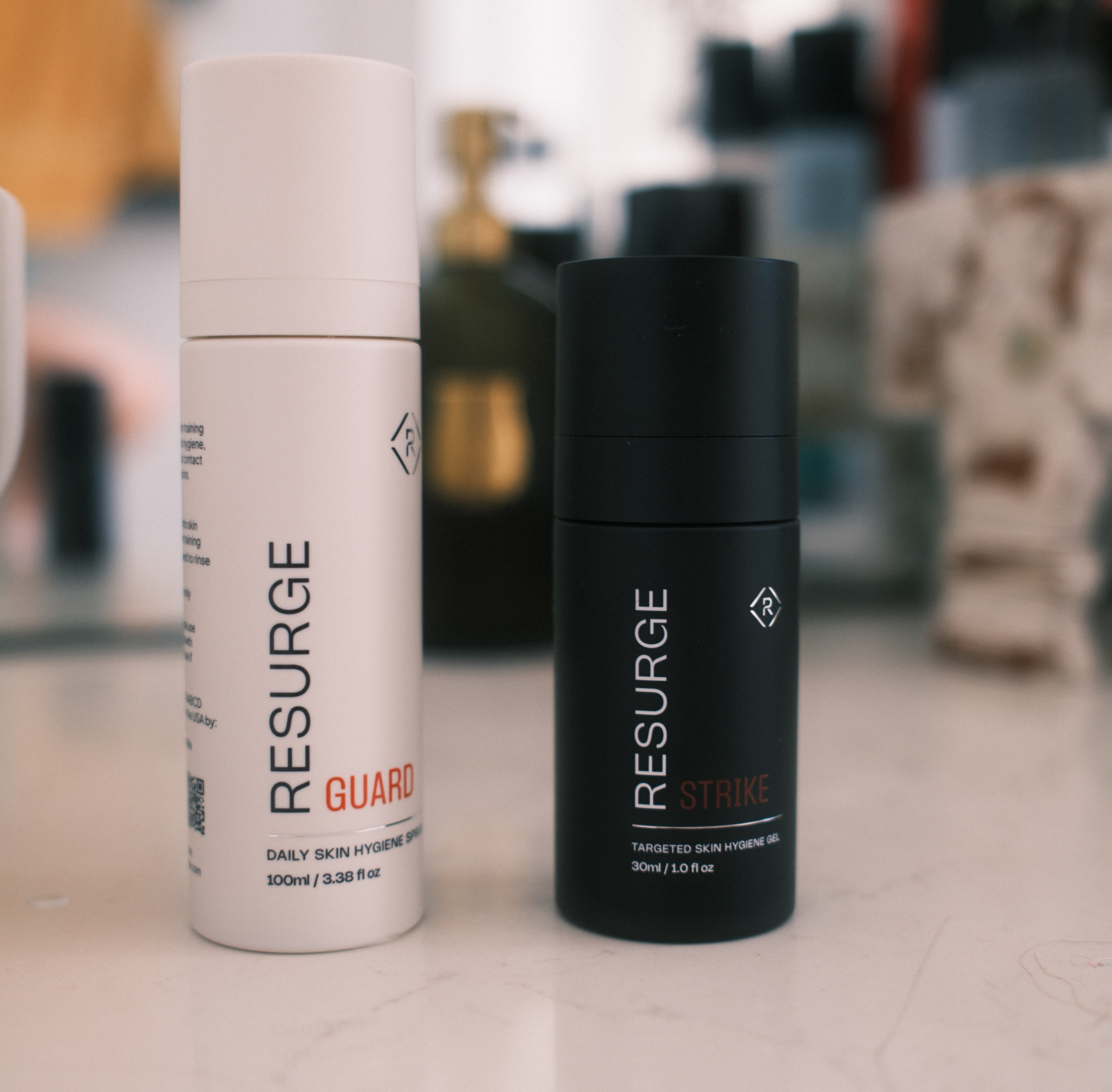 Two skincare bottles, one white labeled 'Guard' and one black labeled 'Strike', on a countertop.
