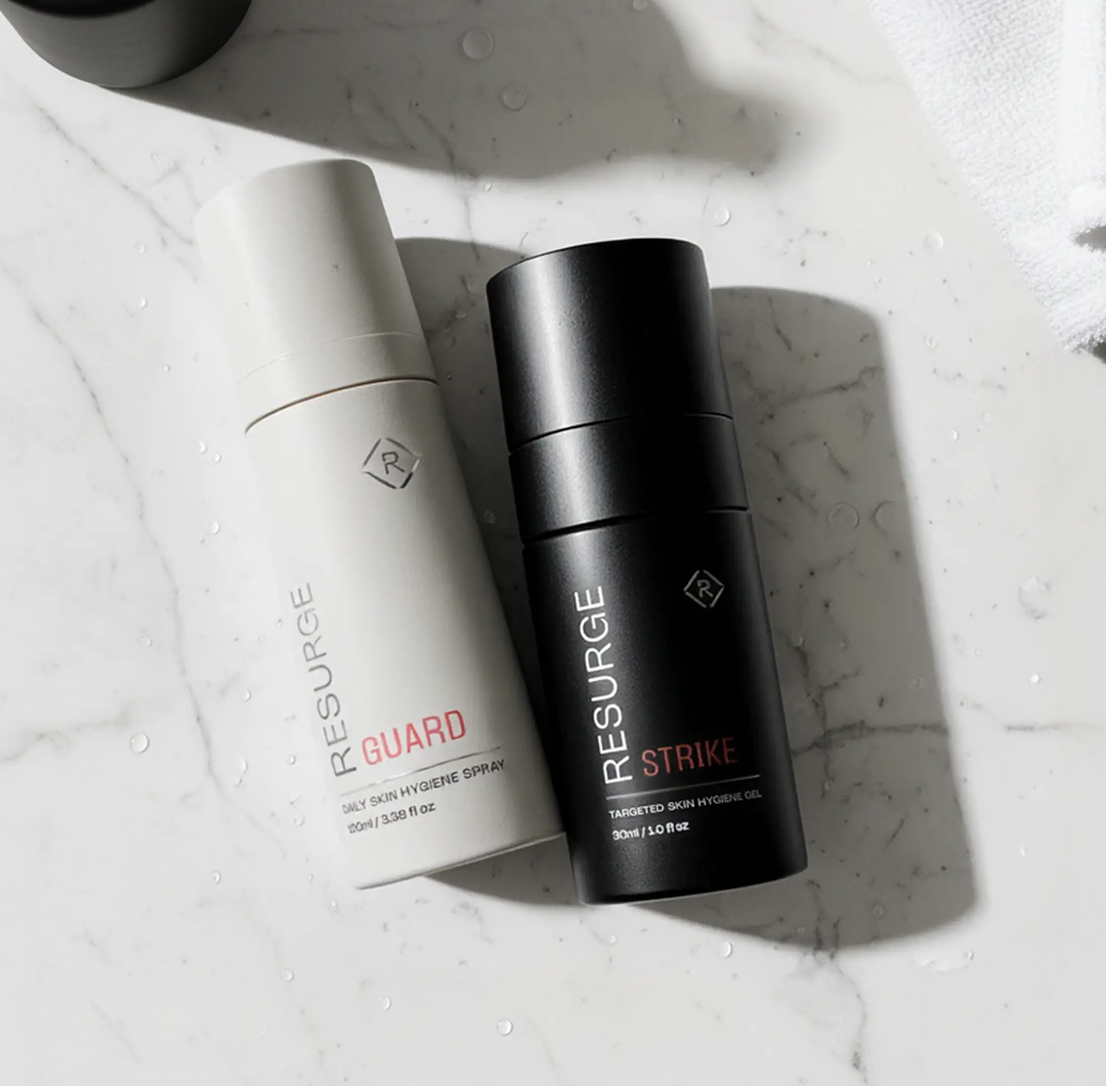 Two skincare bottles labeled 'Guard' and 'Strike' on a marble surface.