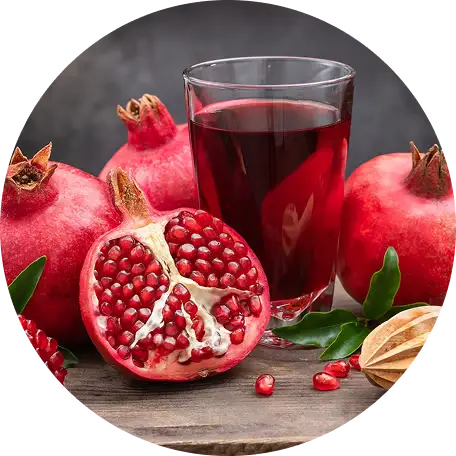 Pomegranates and a glass of pomegranate juice on a wooden surface.
