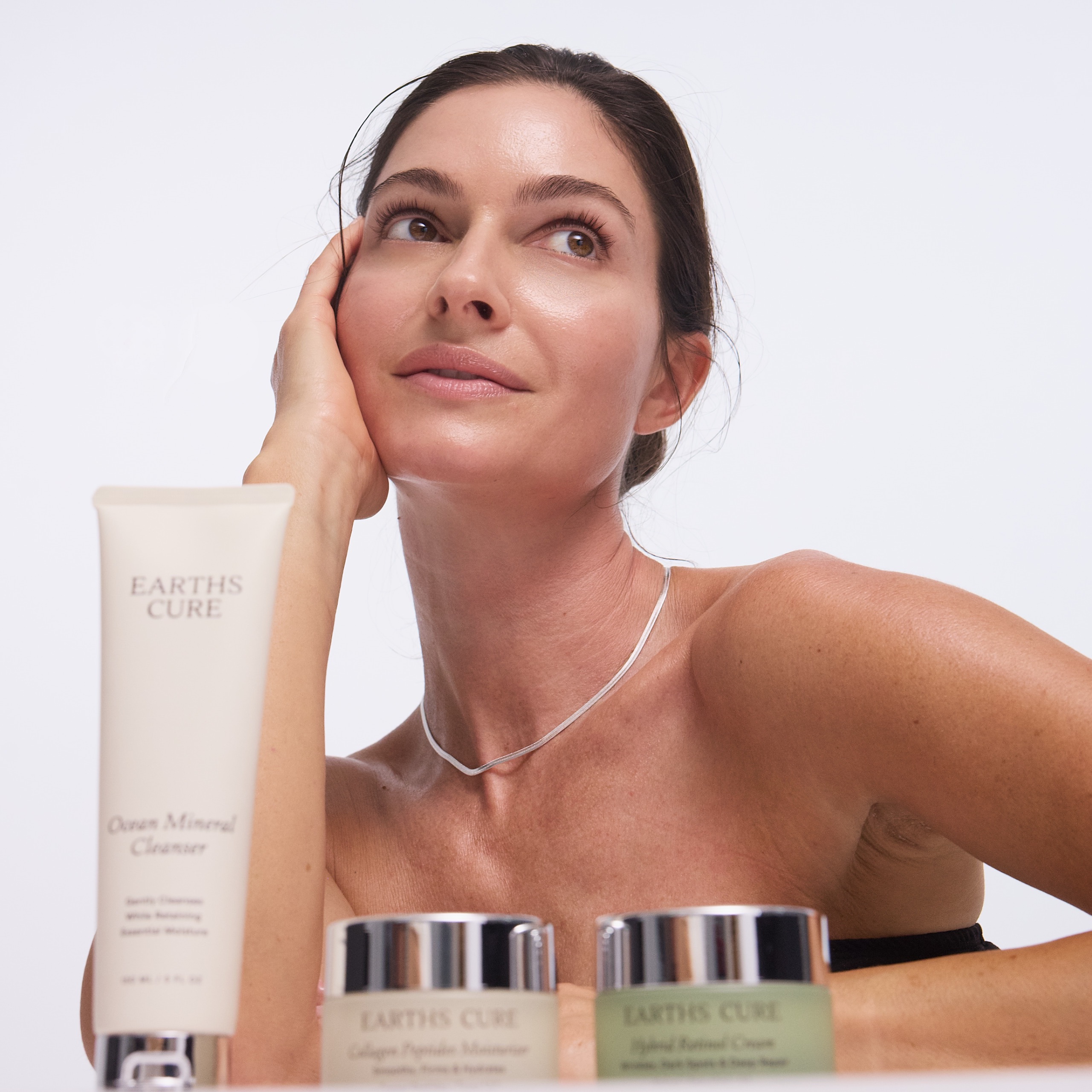 Woman posing with skincare products labeled Earth's Cure.
