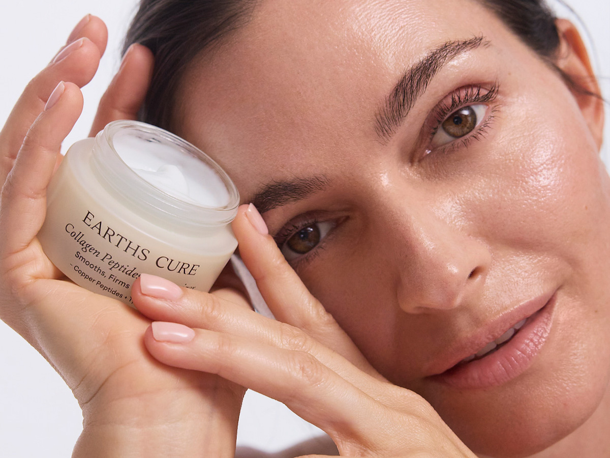 Person holding a jar of skincare cream close to their face.