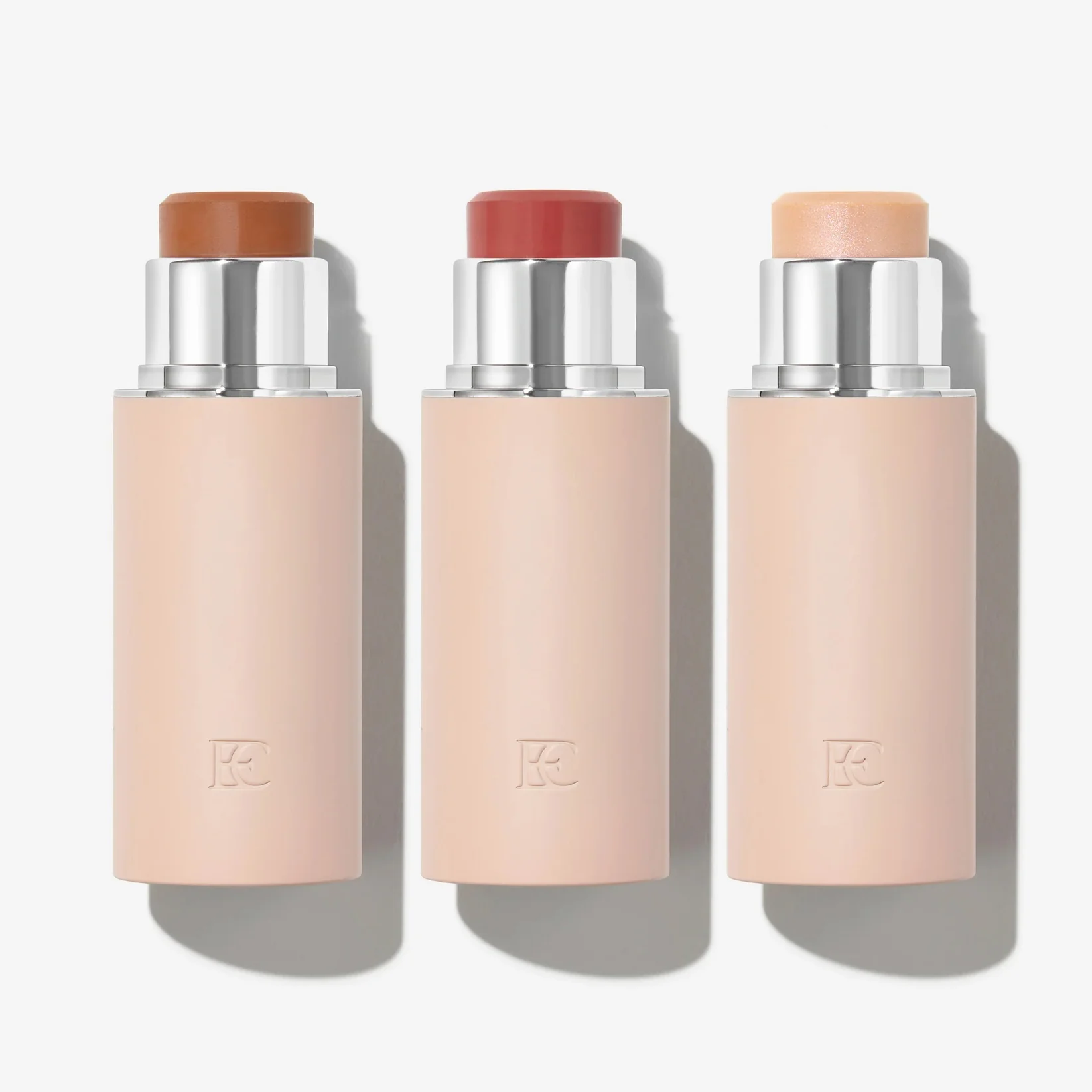 Three cylindrical makeup sticks with different shades and silver tops.