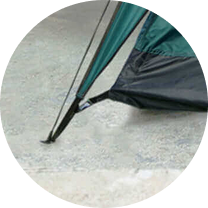 Tent corner with pole secured to the ground.