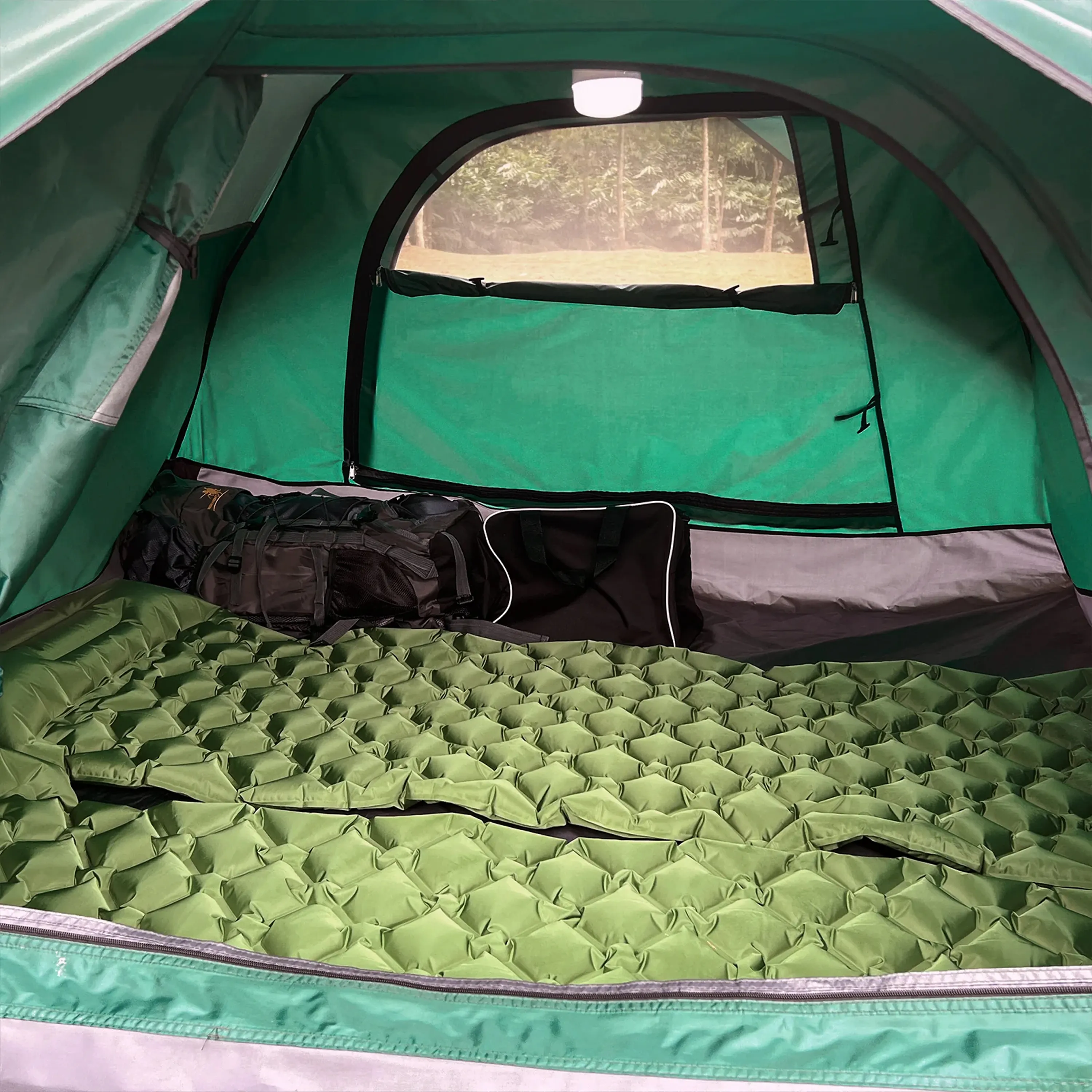 Interior of a green tent with sleeping pad and bags inside.