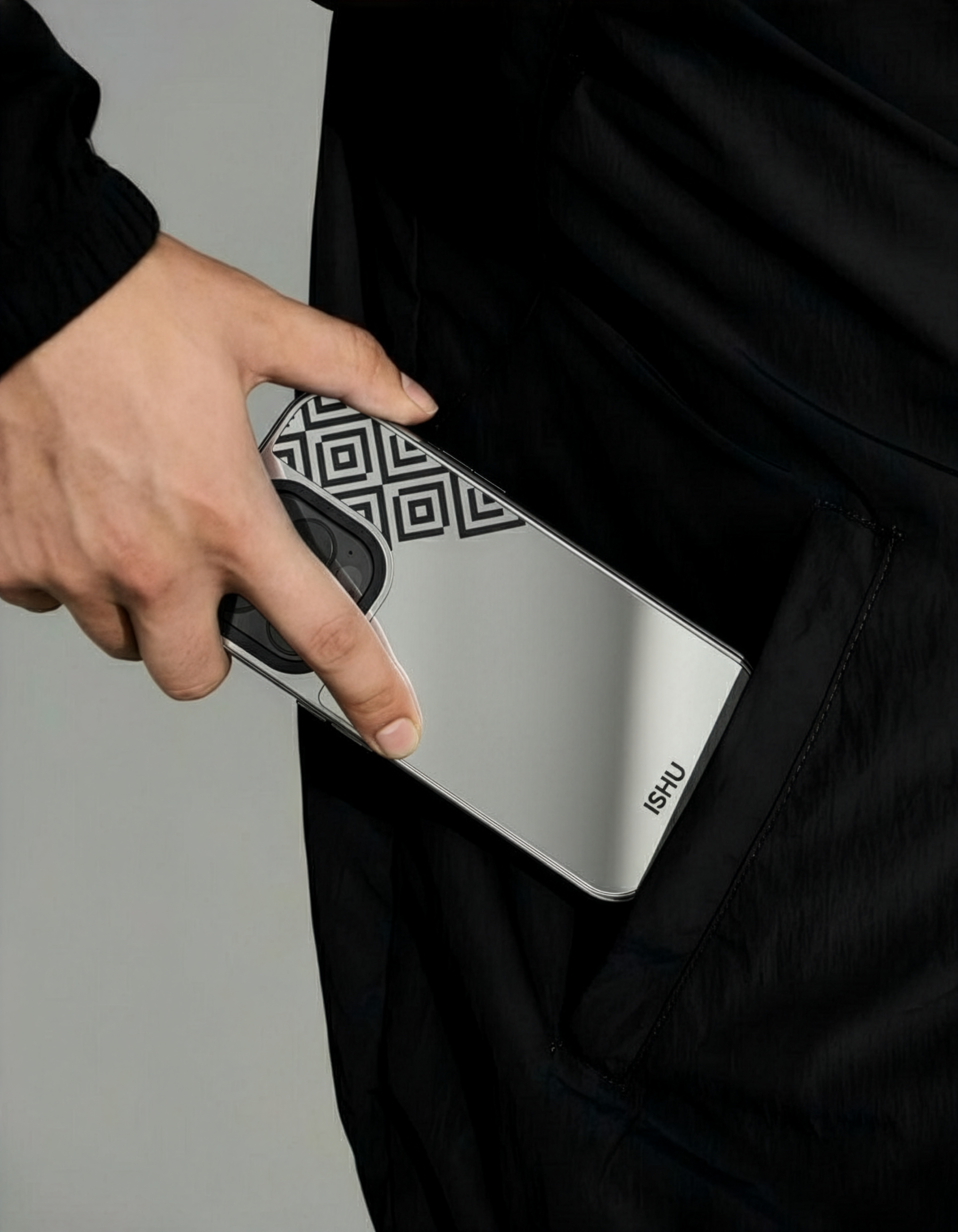 A hand holding a phone with a geometric pattern, partially inserted into a pocket.