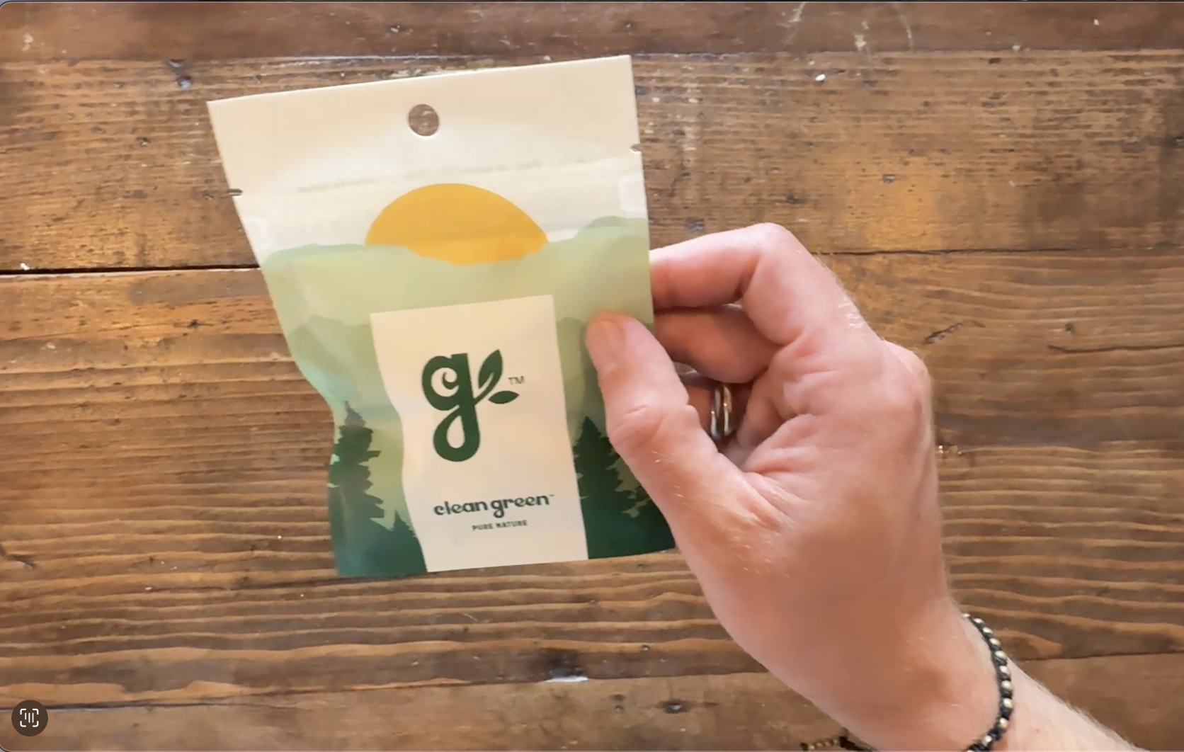 Hand holding a small package with a nature-themed design.
