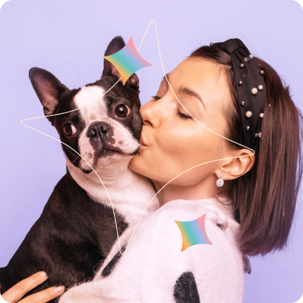 A woman wearing a pearl headband kisses a Boston Terrier dog on the cheek against a purple background.