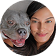 A close-up, circular photo of a smiling woman with long dark hair and a small grey dog.