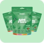 Three green pouches of Buddy SOS Flora pet supplement on a light green background.