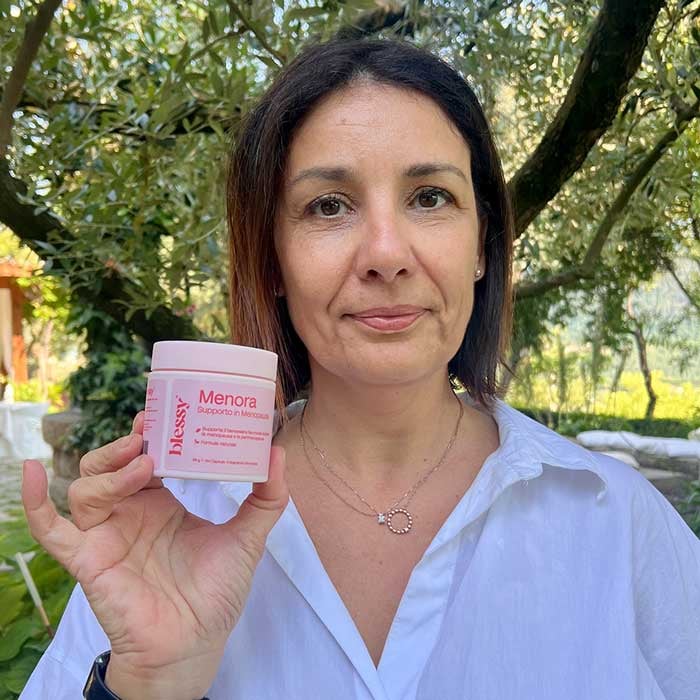 Person holding a jar labeled 'Menora' in an outdoor setting.