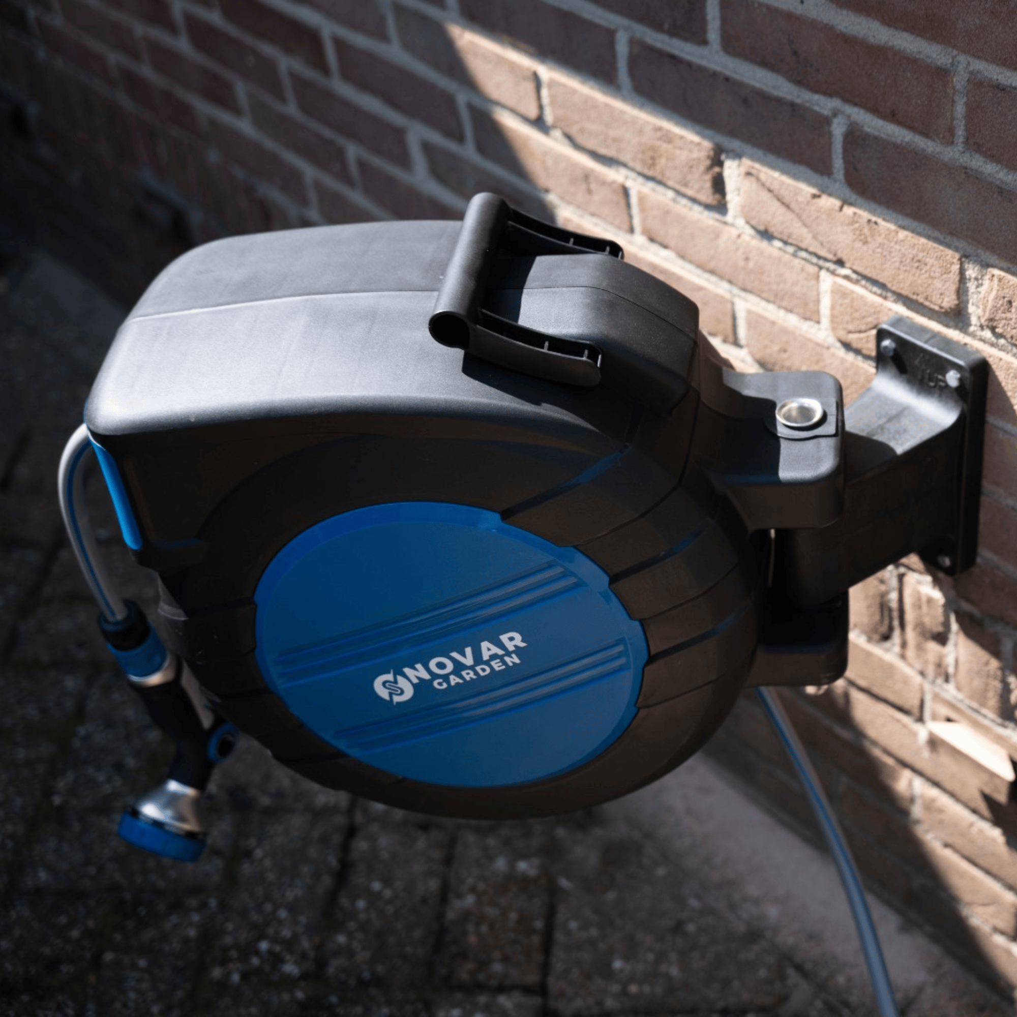 Wall-mounted retractable garden hose reel with blue and black casing.