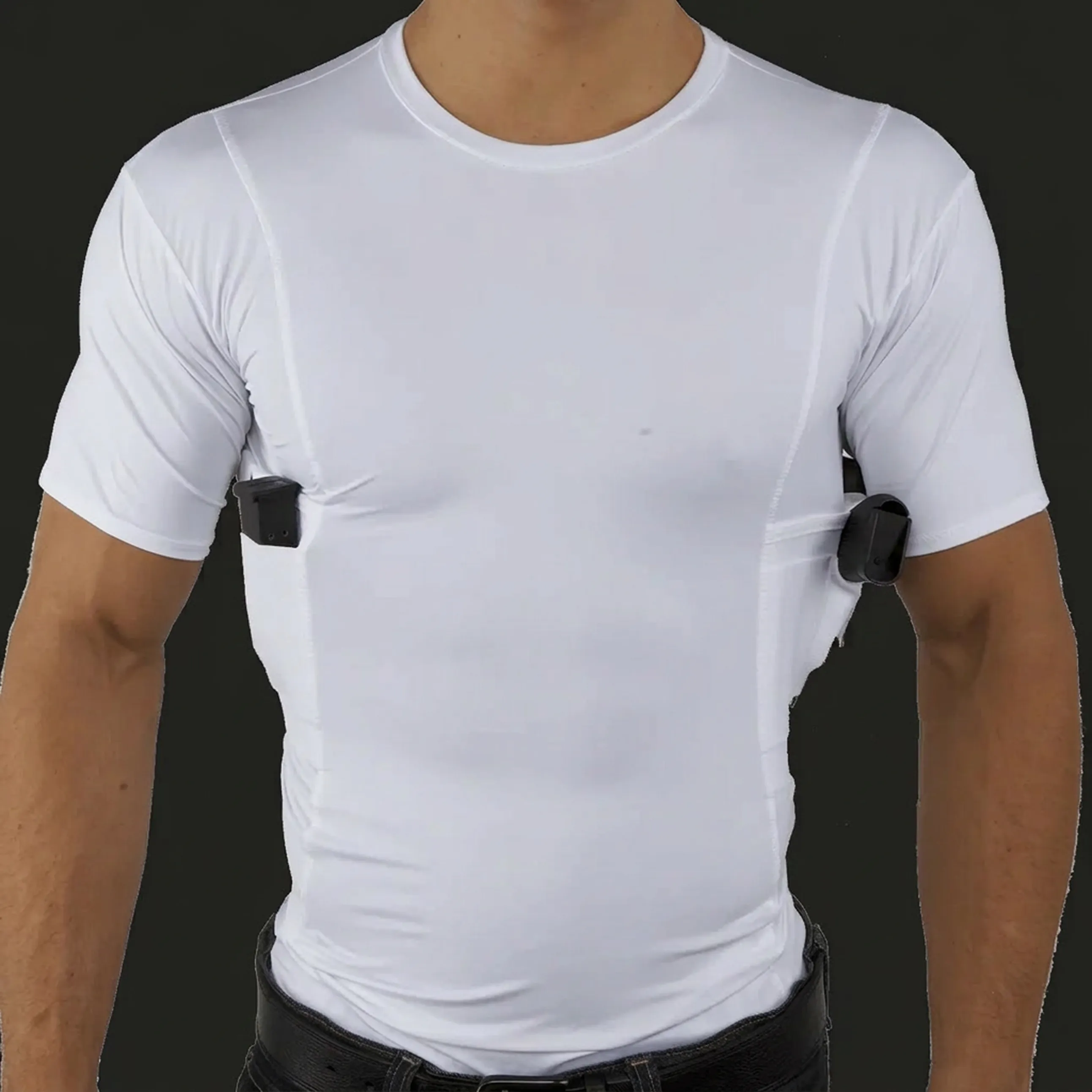 A man models a white compression t-shirt with built-in underarm holsters holding a pistol and a magazine.