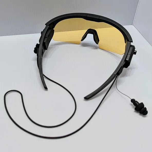 A pair of black-framed safety glasses with yellow lenses and an attached earplug and neck strap.